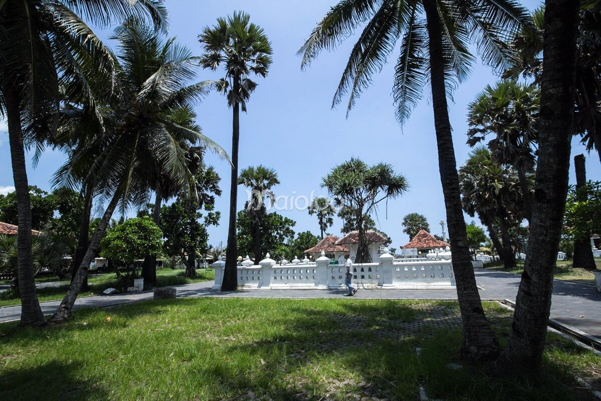 The Cepuri Parangkusumo complex in the afternoon, with palm trees and traditional buildings under a clear sky.