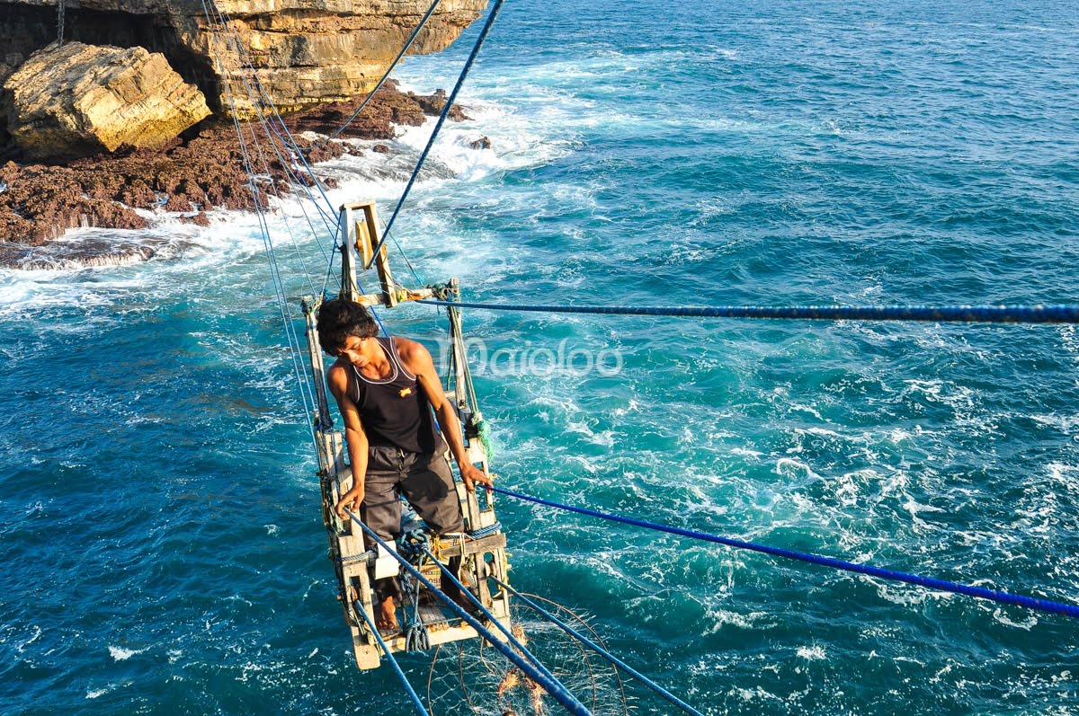 A man crossing the ocean on a gondola at Timang Beach.