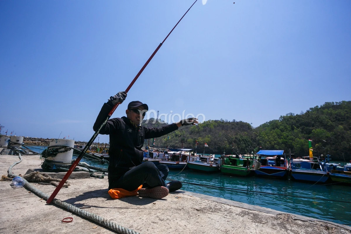 A fisherman preparing his fishing rod at Sadeng Beach Port.