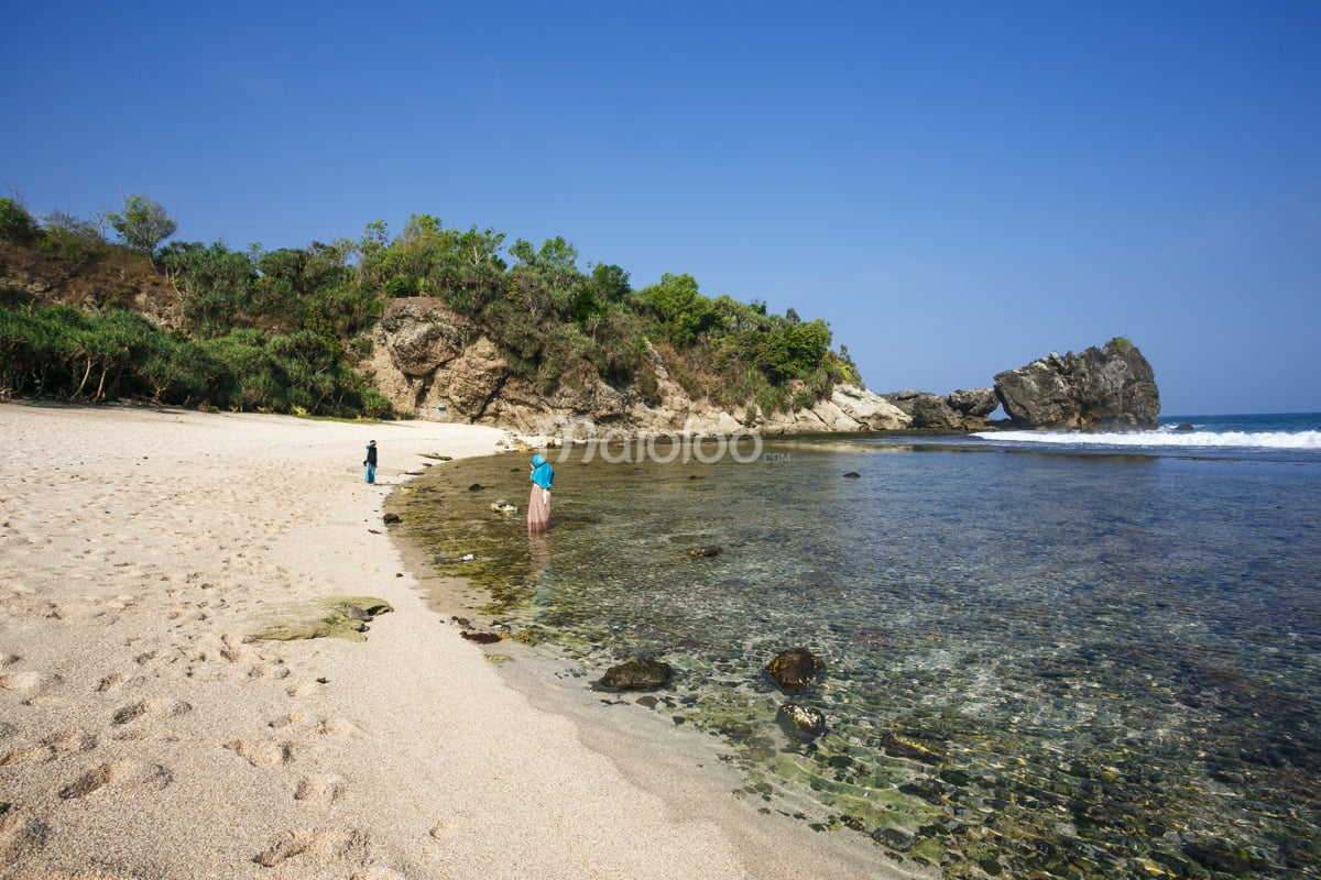 Visitors enjoying the clear waters and soft sand at Jungwok Beach, Yogyakarta.
