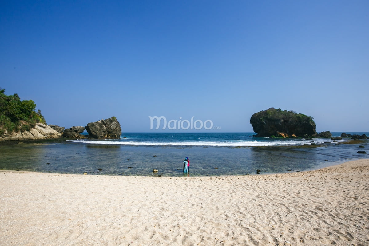 A tourist playing in the shallow waters of Jungwok Beach, Yogyakarta.