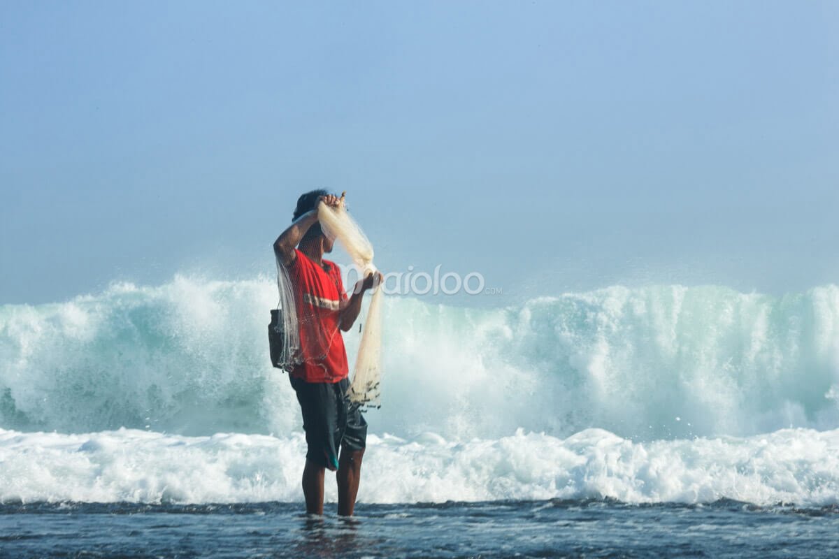 A fisherman casting a net at Pok Tunggal Beach.