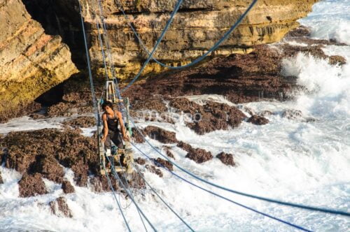 A man crossing the ocean on a gondola at Timang Beach.