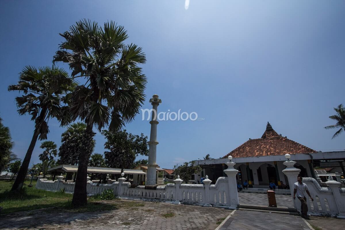 A mosque in the Cepuri Parangkusumo complex, surrounded by palm trees under a clear sky.