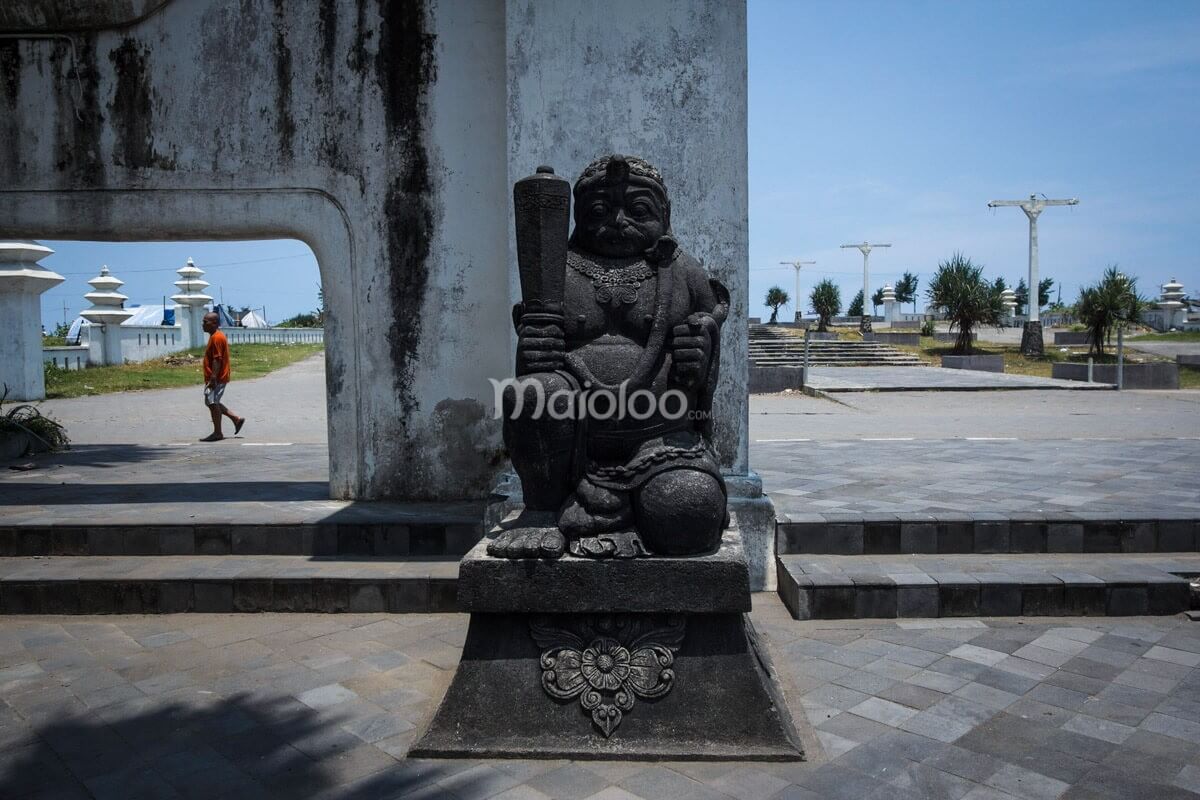 A statue in the Cepuri Parangkusumo complex, with a person walking in the background.