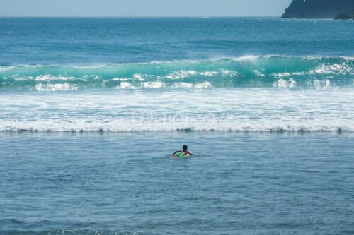 A surfer paddling out to catch a wave at Wediombo Beach, Yogyakarta.