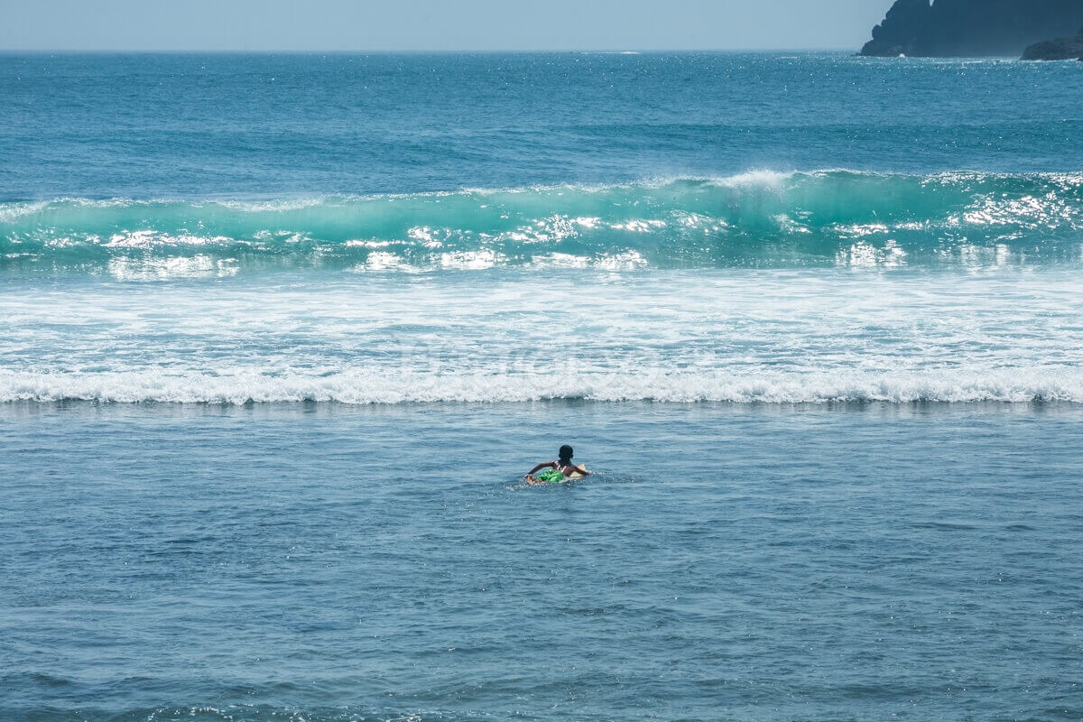 A surfer paddling out to catch a wave at Wediombo Beach, Yogyakarta.
