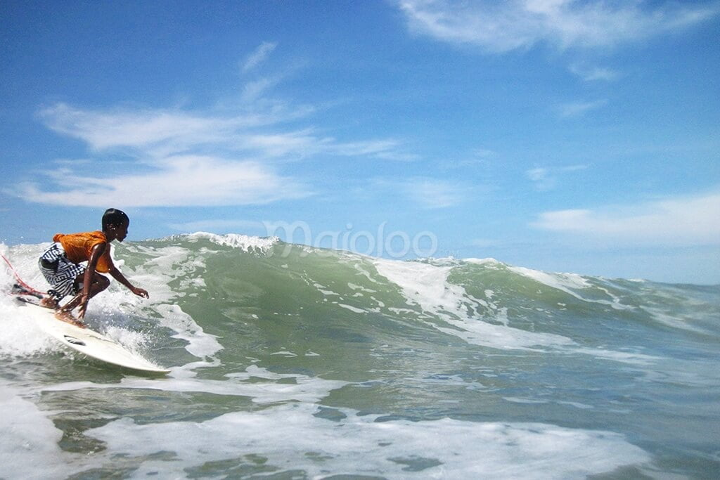 A surfer riding a wave at Parangtritis Beach.