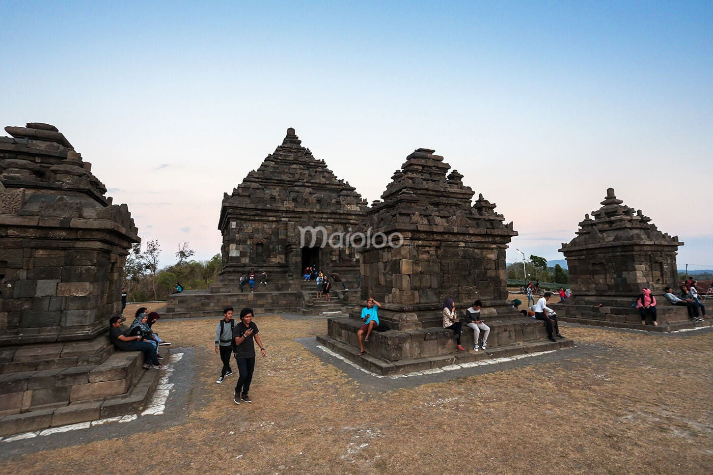 People walking and sitting around the stone temples of Ijo Temple.