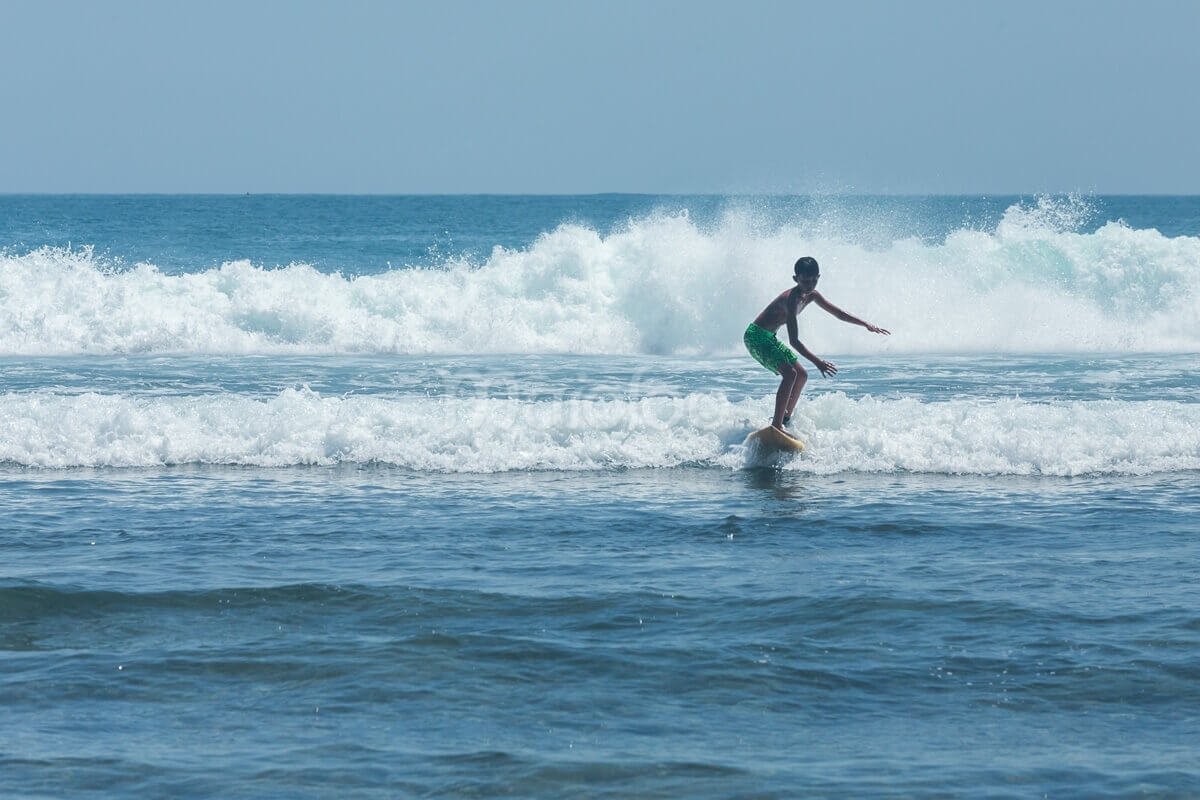 A young boy surfing a wave at Wediombo Beach, Yogyakarta.