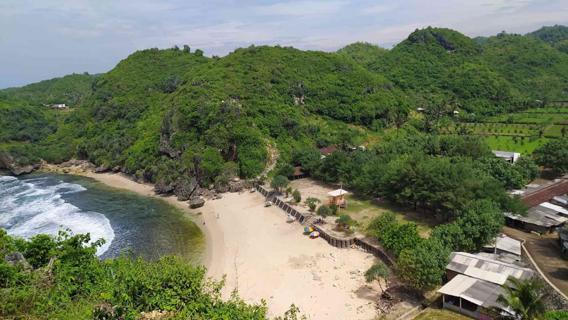 Aerial view of Nguyahan Beach surrounded by green hills.