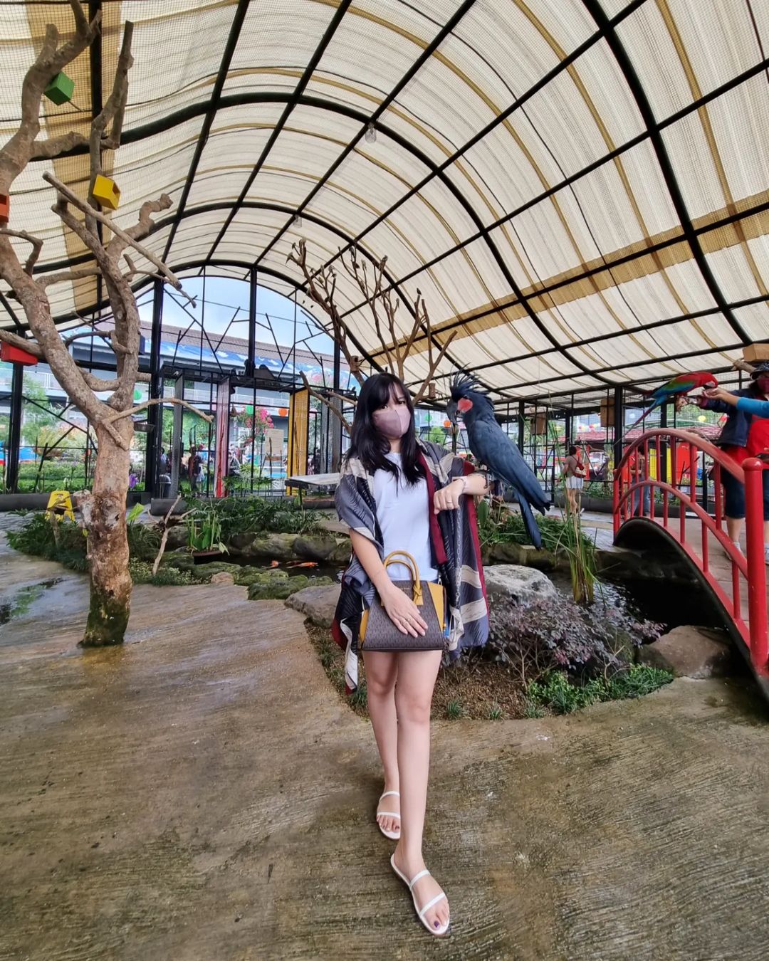 A woman holding a black cockatoo at the aviary in Suraloka Interactive Zoo.