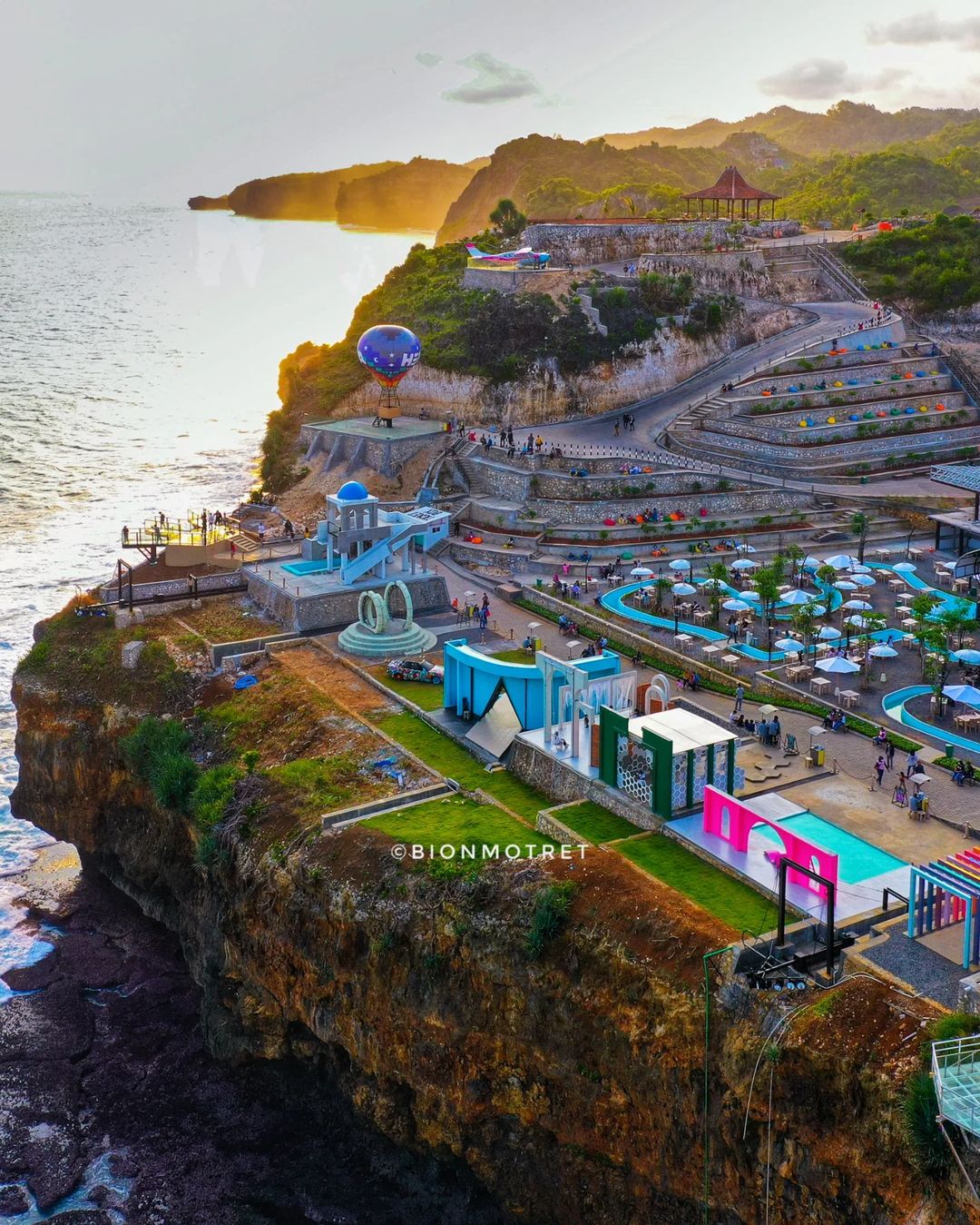 Aerial view of HeHa Ocean View with colorful attractions and ocean cliffs in daylight.