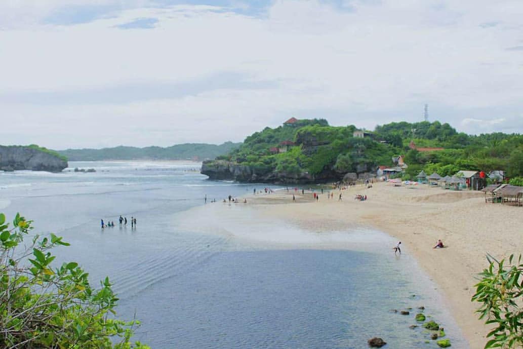 People enjoying the sandy shore and clear waters at Sundak Beach on a bright day.