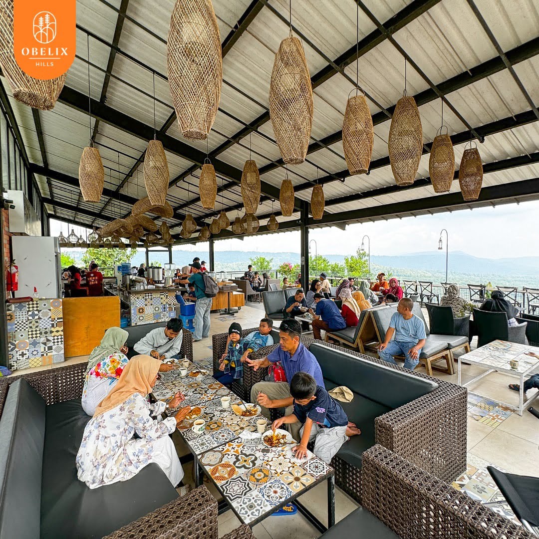 People dining at Pulen Kopi Ponti, an outdoor restaurant with hanging wicker lanterns and a view of green landscapes.