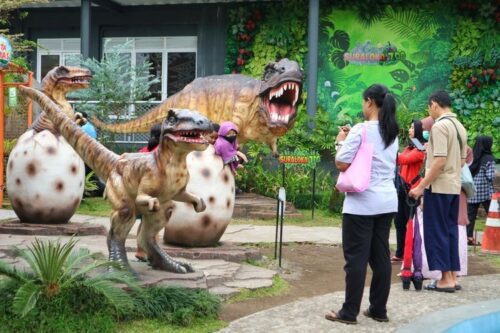 Children and adults exploring dinosaur statues at Suraloka Interactive Zoo.