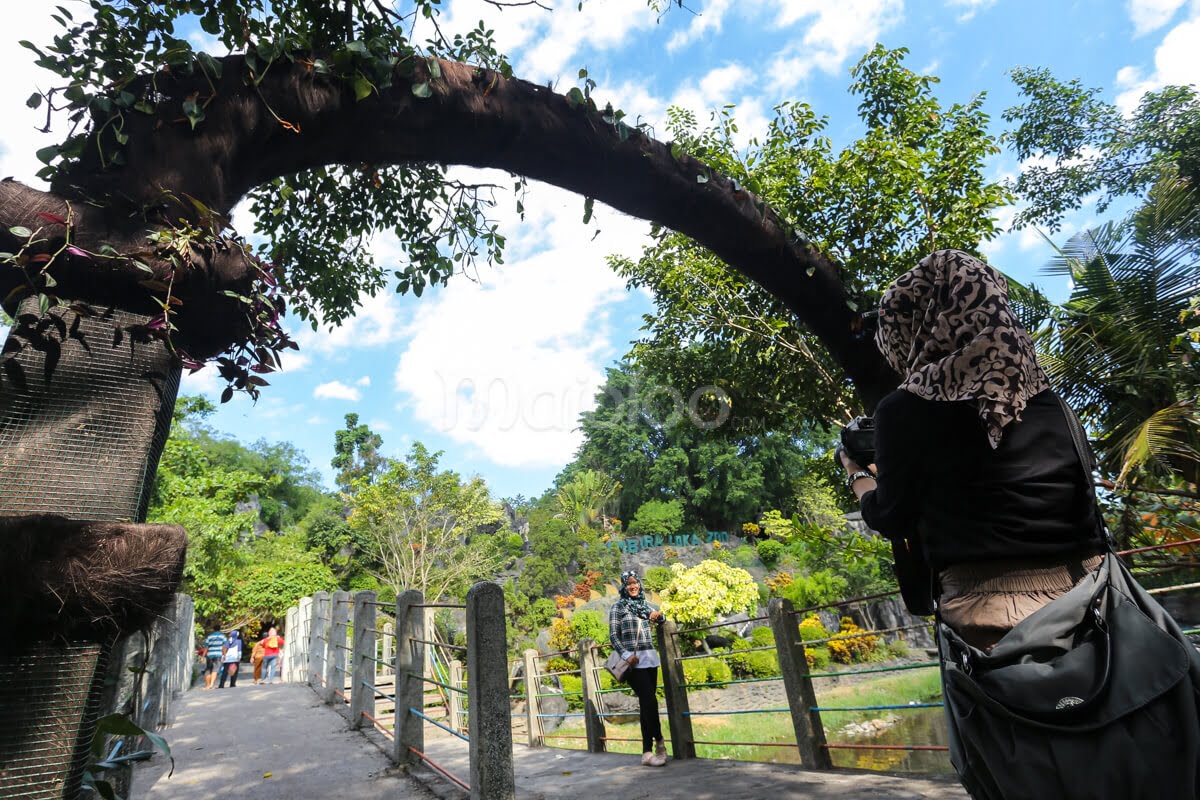 Visitors walking under an arch at the exit of Gembira Loka Zoo.