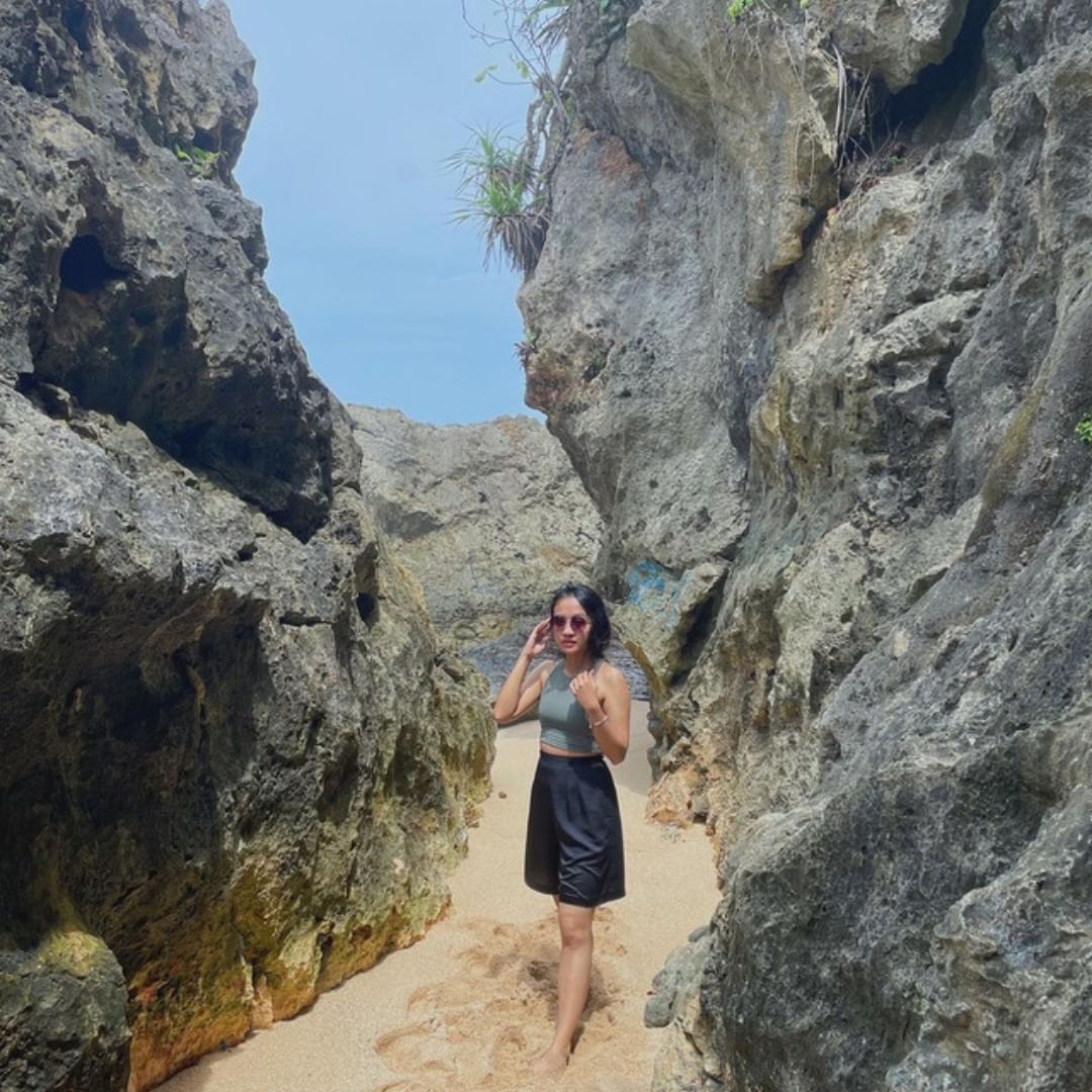 Woman standing between large rocks at Watulawang Beach.