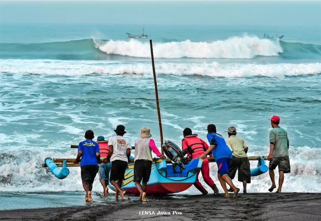 Fishermen push a boat into the sea at Depok Beach.