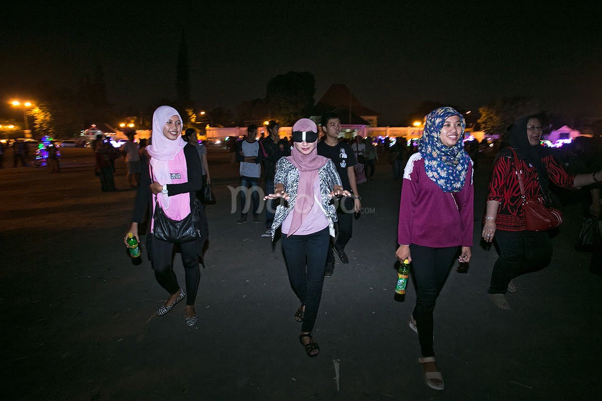 A group of visitors playing the masangin game at Alun-Alun Kidul in Yogyakarta at night.