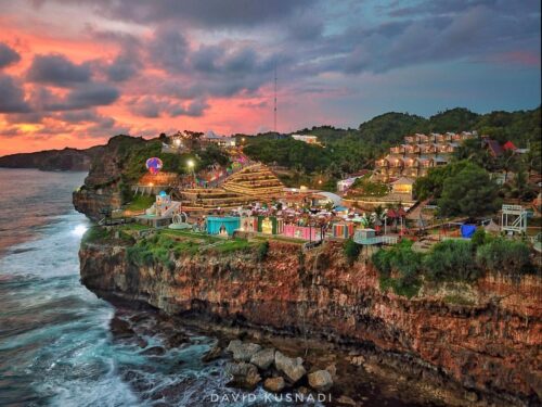 Aerial view of HeHa Ocean View with vibrant lights and ocean cliffs at sunset.