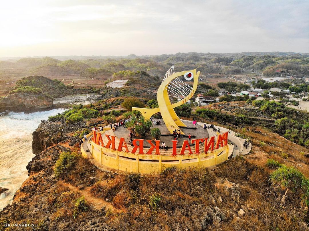 Aerial view of Krakal Beach sign with a large yellow fish statue and surrounding landscape.