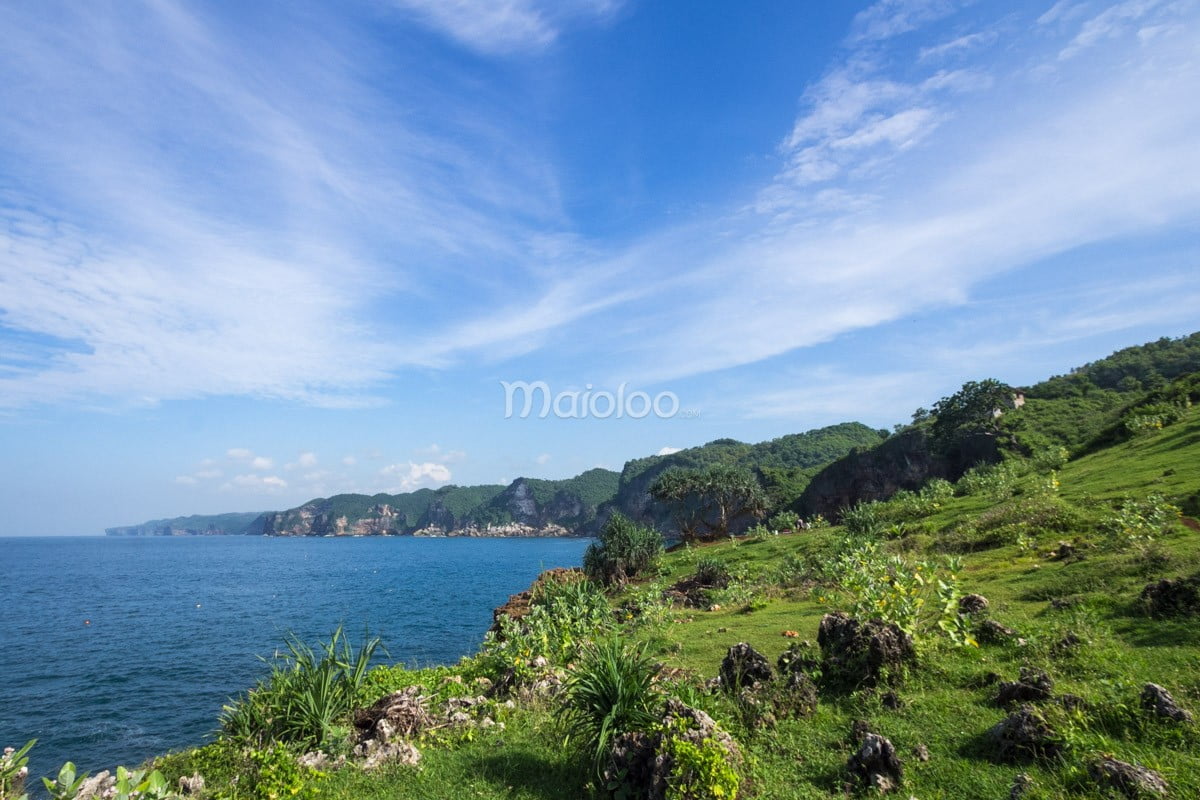 Green hills and blue ocean at Kesirat Beach on a sunny morning.