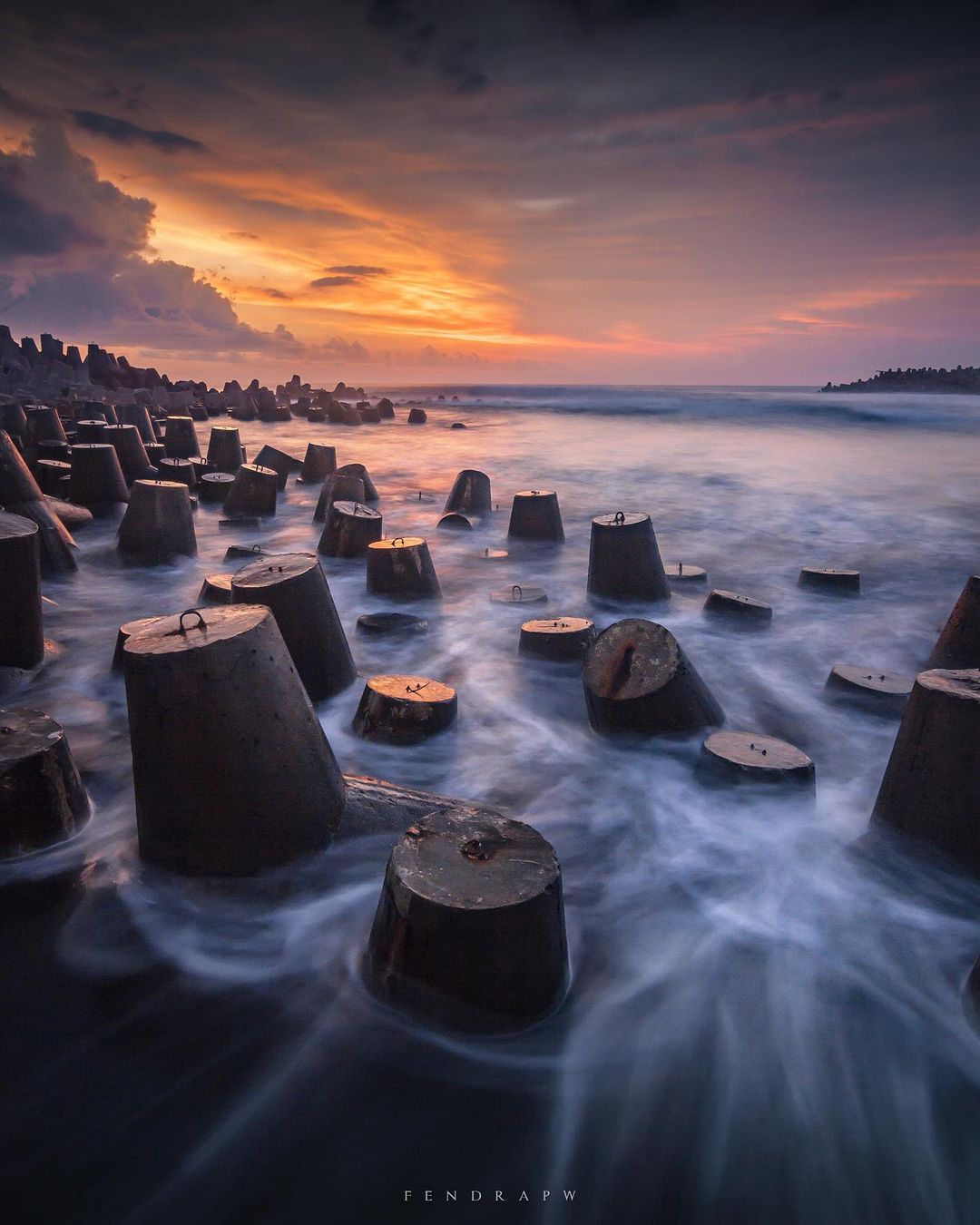 Wave breakers at Glagah Beach during a colorful sunset.