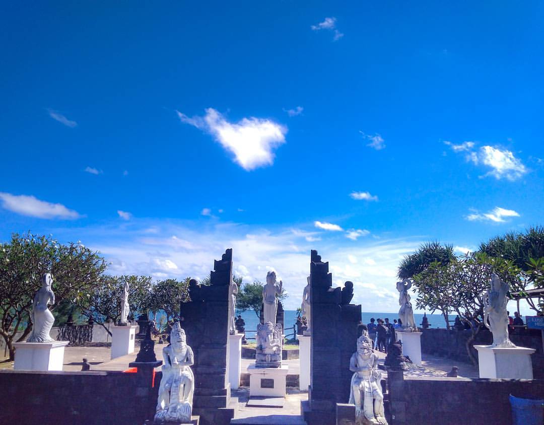 Hindu statues and gates at Ngobaran Beach under a bright blue sky.