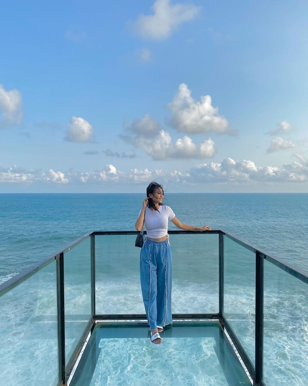 A woman standing on a glass platform with an ocean view at HeHa Ocean View.