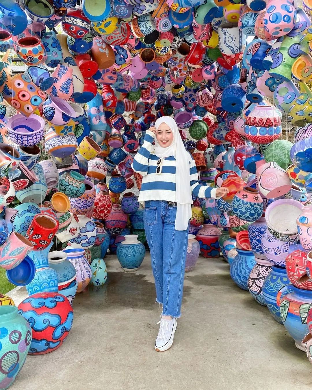 Woman posing under a vibrant canopy of colored pots at Obelix Hills.