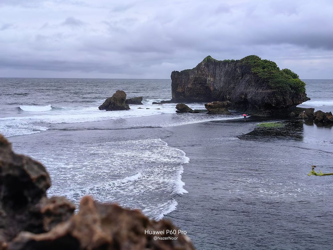 Large rock formations in the sea at Sundak Beach with gentle waves and cloudy skies.