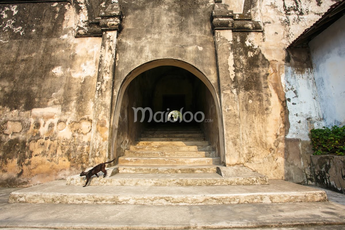 A weathered stone staircase leading up to an arched entrance at Pasarean Ledhoksari in Taman Sari, Yogyakarta.