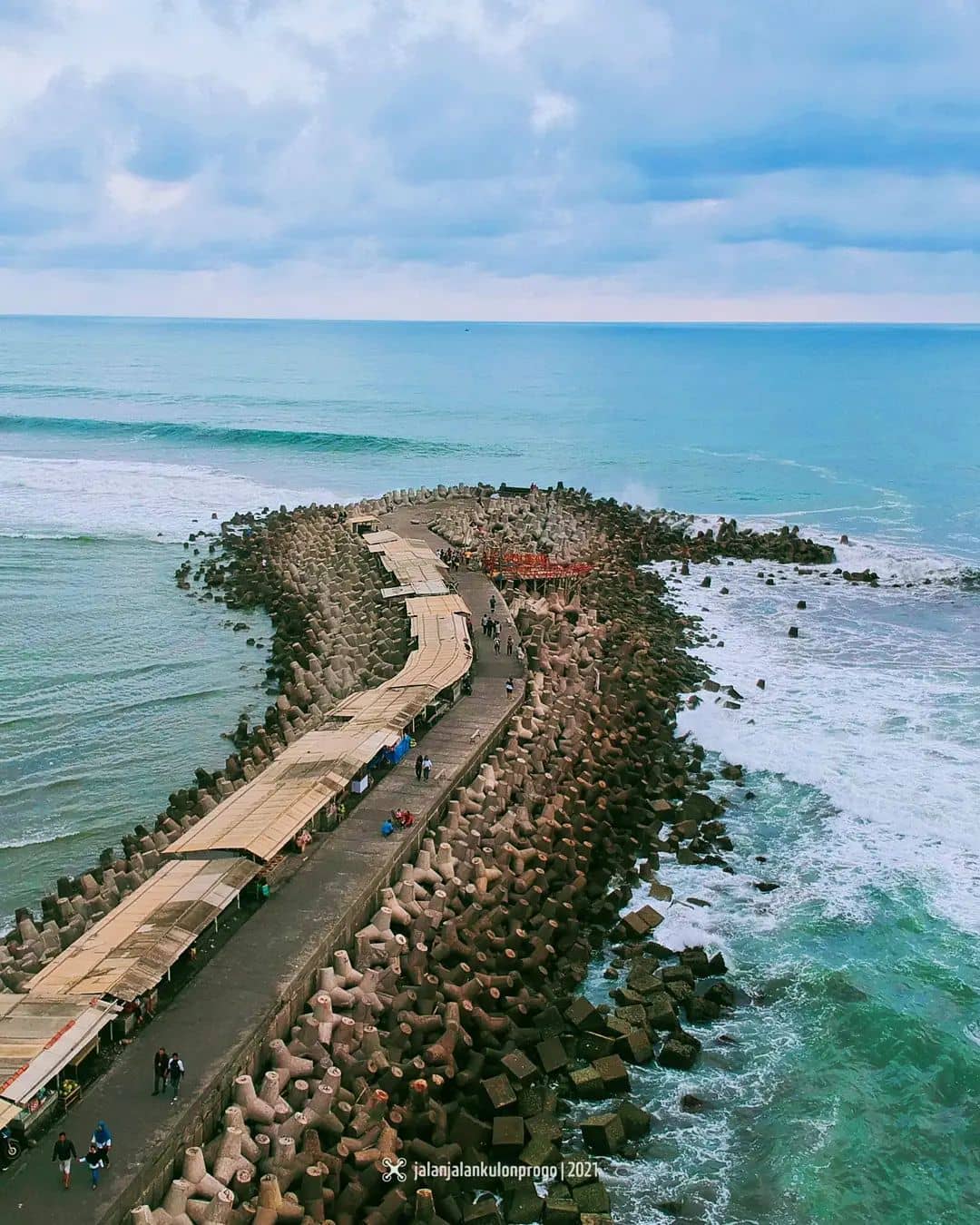 Pathway on the wave breakers at Glagah Beach with people walking and enjoying the view.