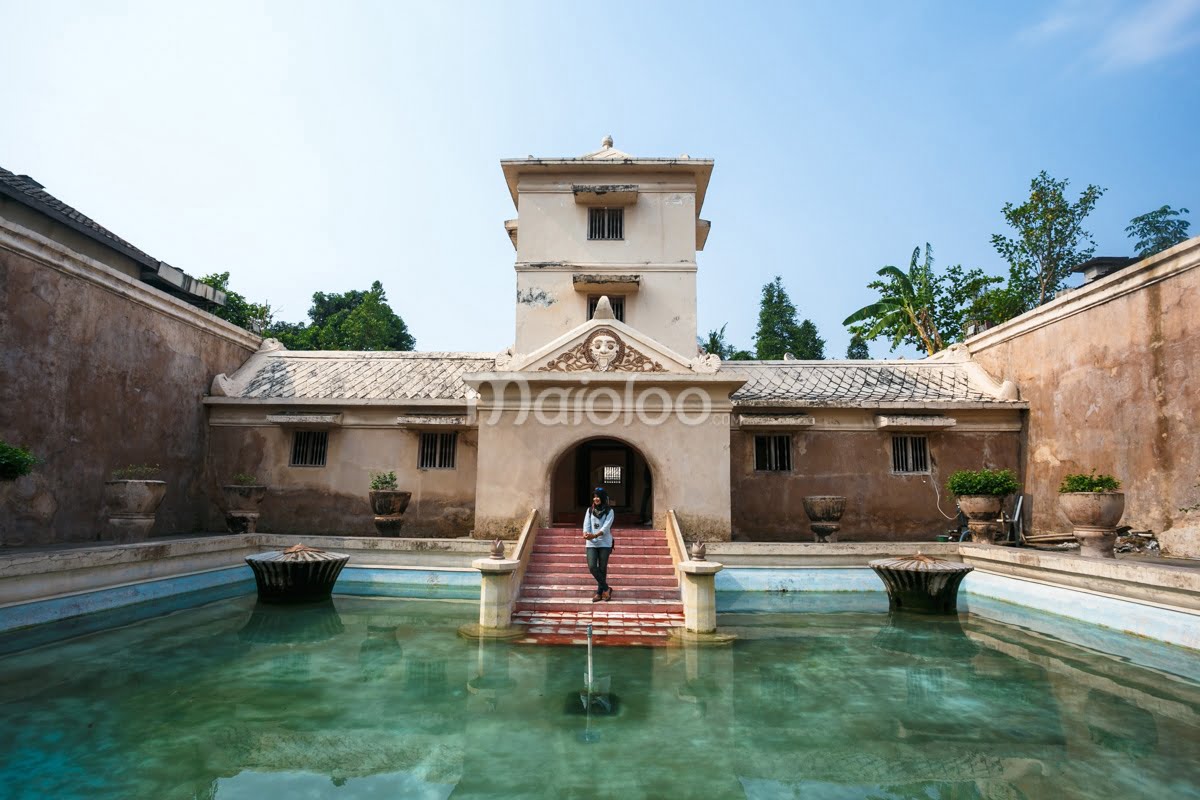 A large pool with a central fountain and steps leading to the building at Umbul Binangun in Taman Sari, Yogyakarta.