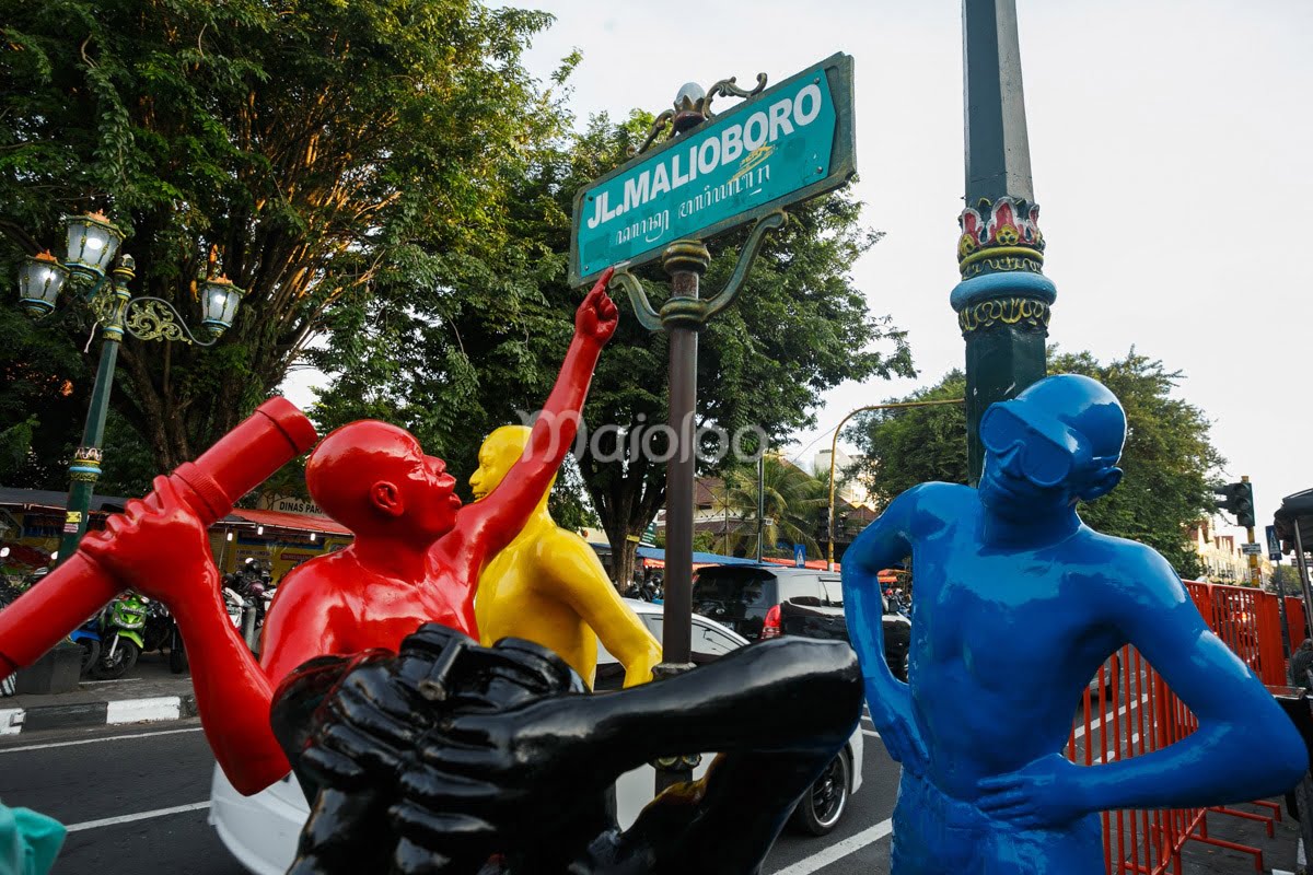 Colorful statues in red, blue, and yellow near a "Jl. Malioboro" street sign.