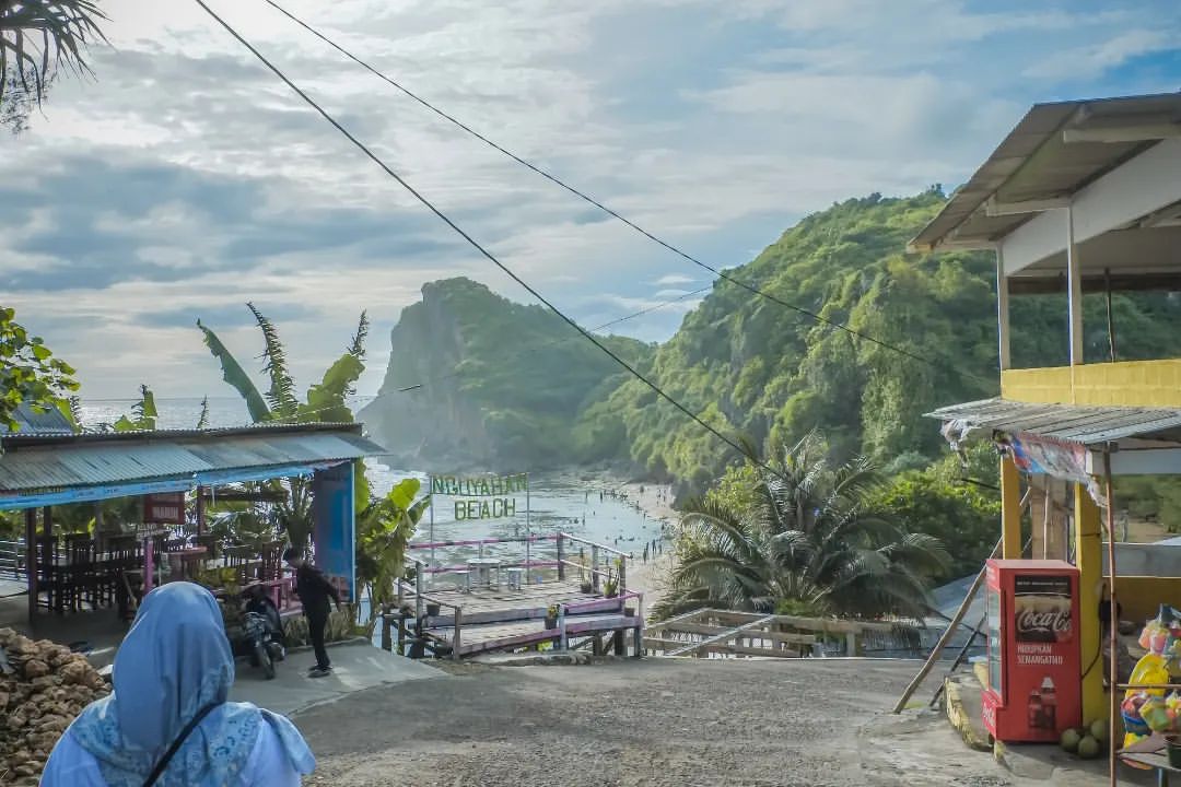 Entrance to Nguyahan Beach with people walking and hills in the background.