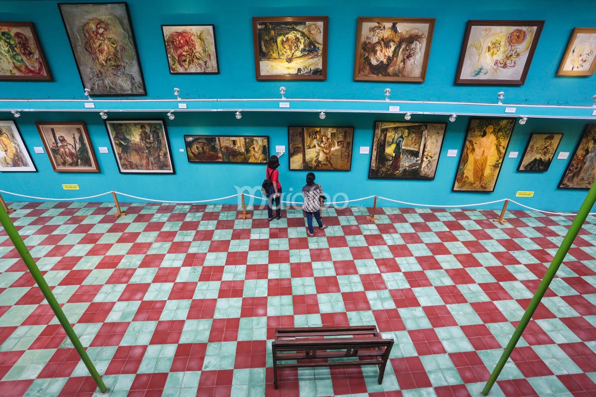 Two people admiring paintings in one of Affandi Museum's galleries.