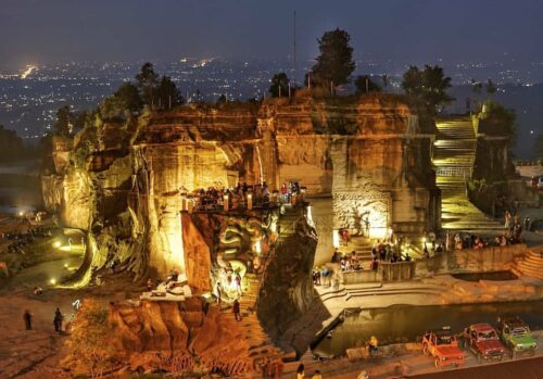 Breksi Cliff illuminated at night with visitors enjoying the scenery.