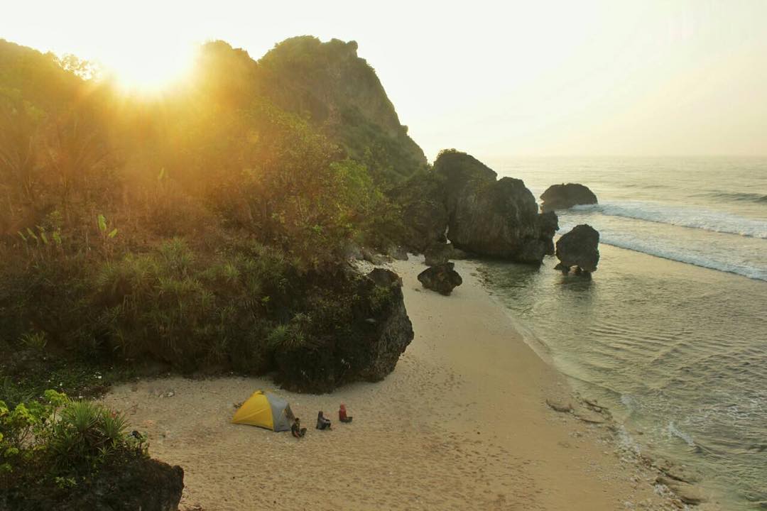 Sunrise over a tent and campers on the sandy beach of Pringjono.