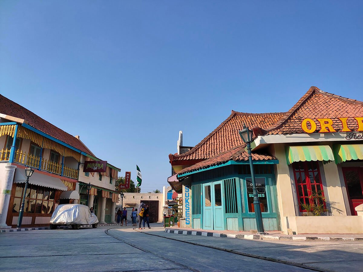 A street scene at Gamplong Studio Alam with old-fashioned buildings and a covered car.