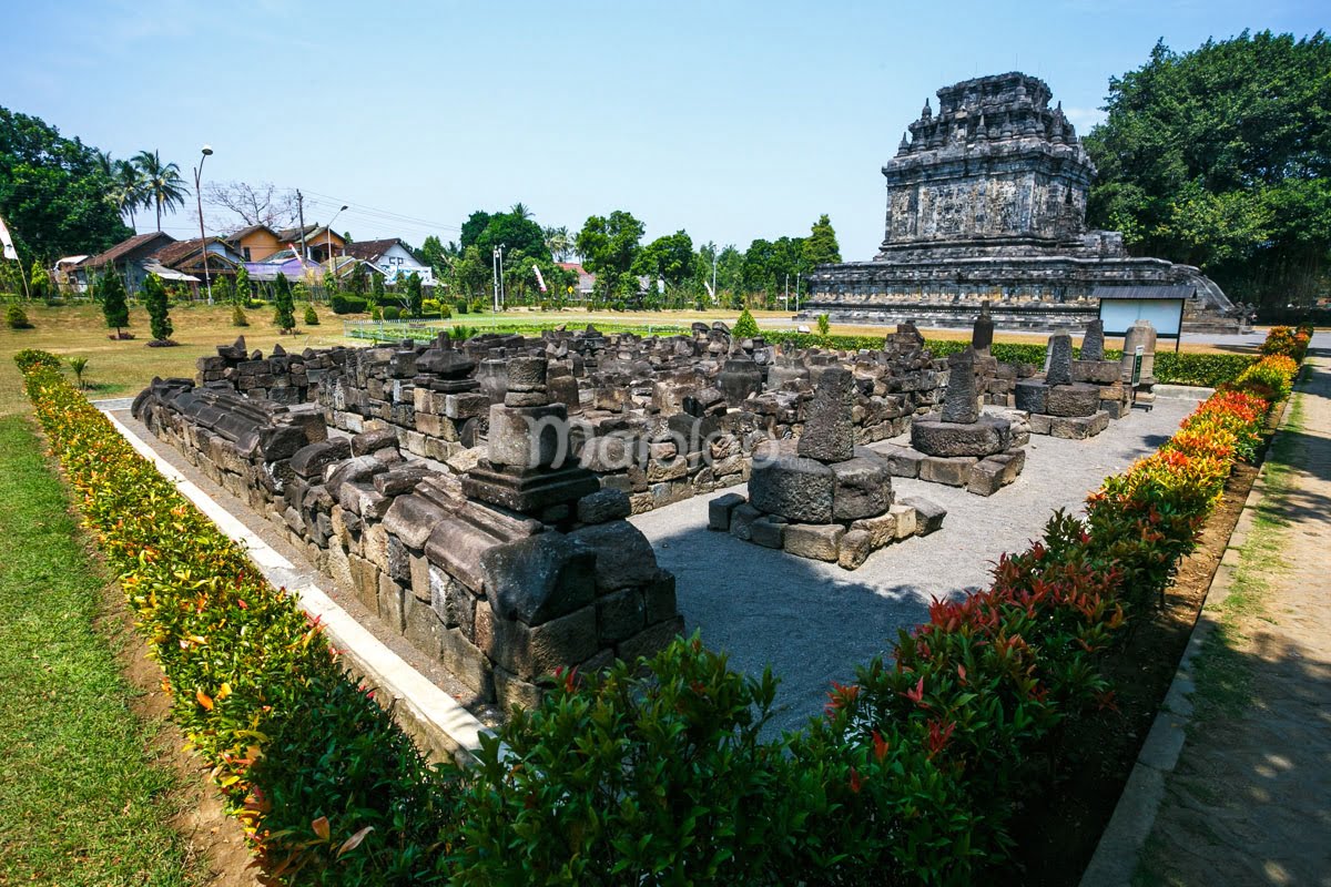 Courtyard of Mendut Temple with ancient stone ruins and greenery.