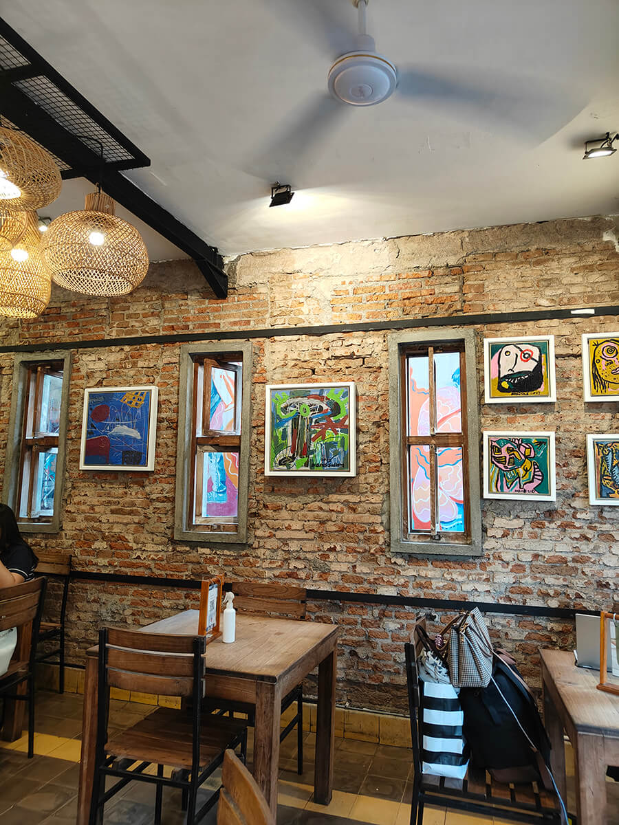 Interior of a cafe in Prawirotaman with brick walls, colorful artwork, and wooden tables and chairs.