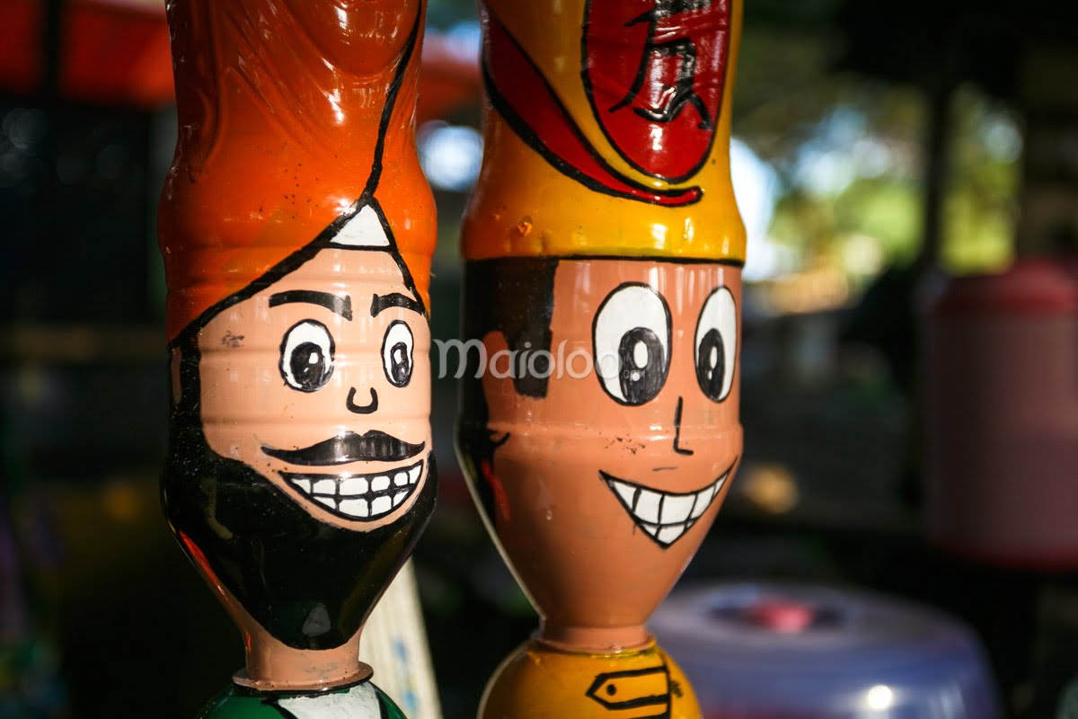 Painted recycled bottles with smiling faces as part of Gardu Action's creations.