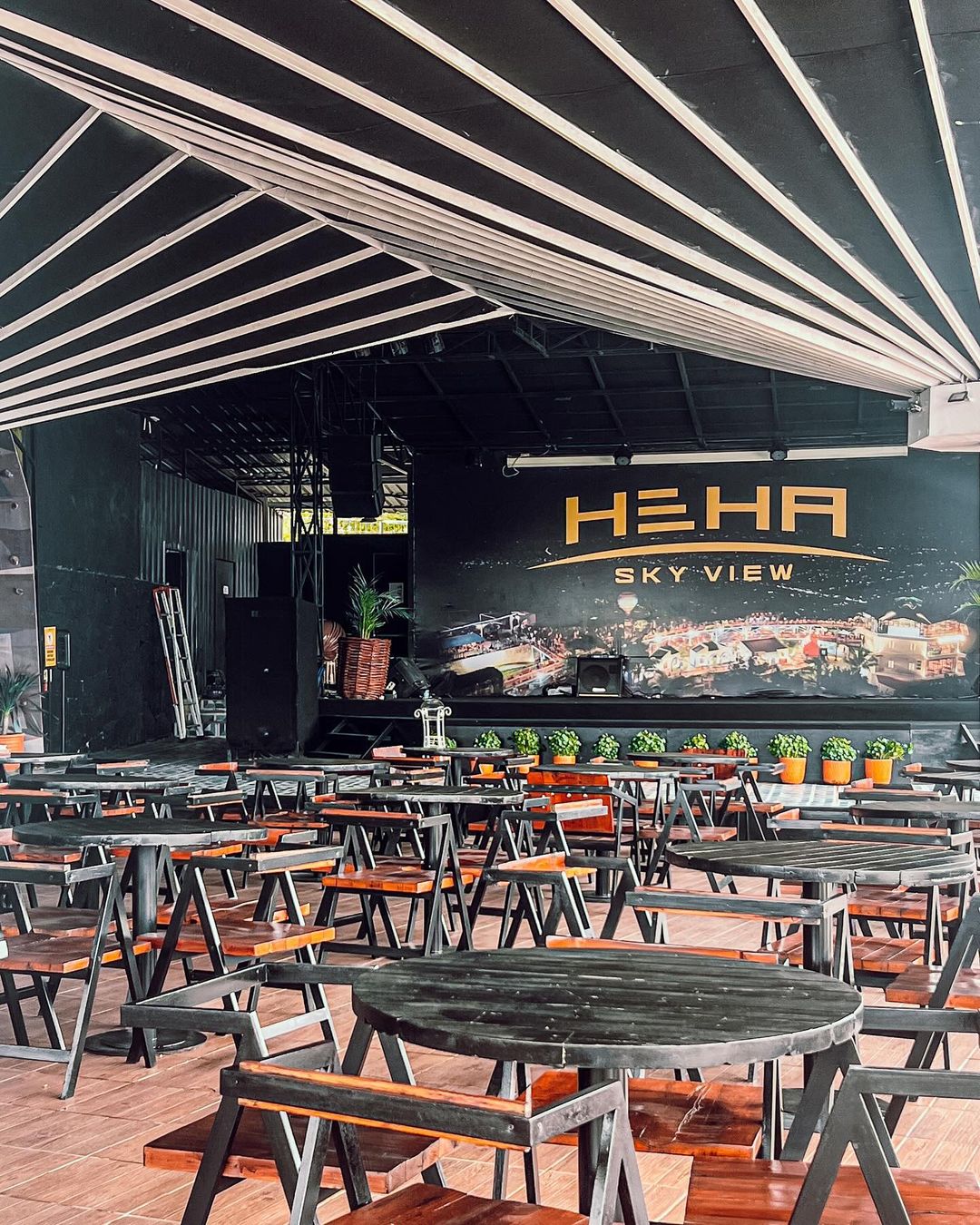 Empty seating area in HeHa Sky View's covered dining area with wooden tables and chairs.