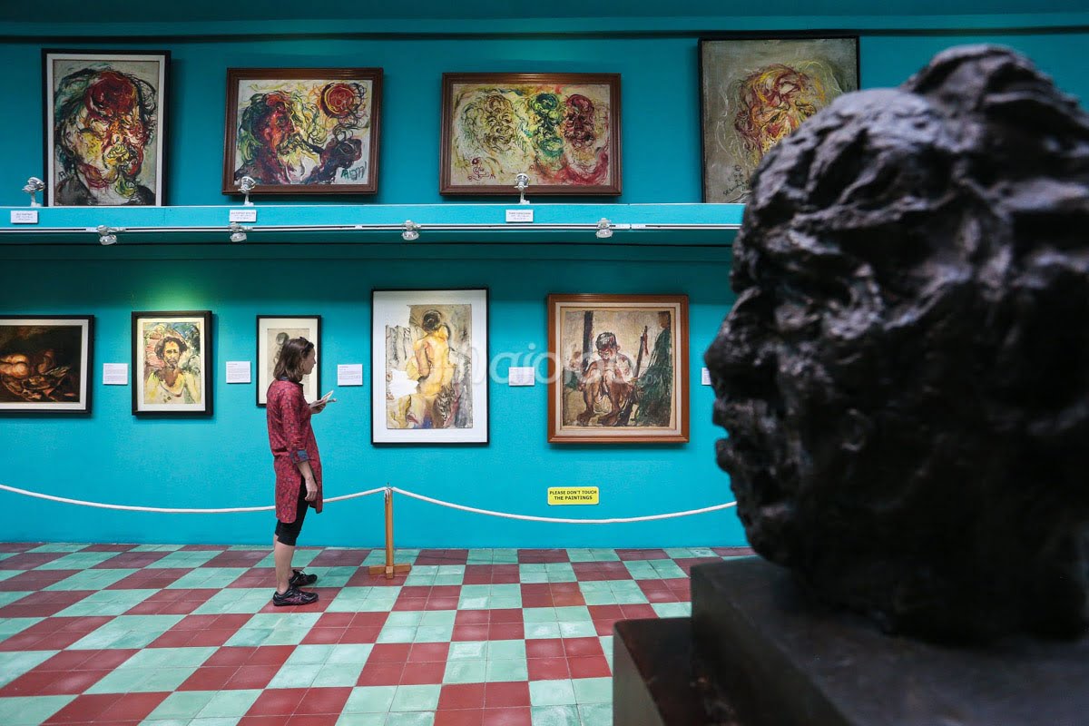 A person observing paintings on the walls in Affandi Museum's gallery.