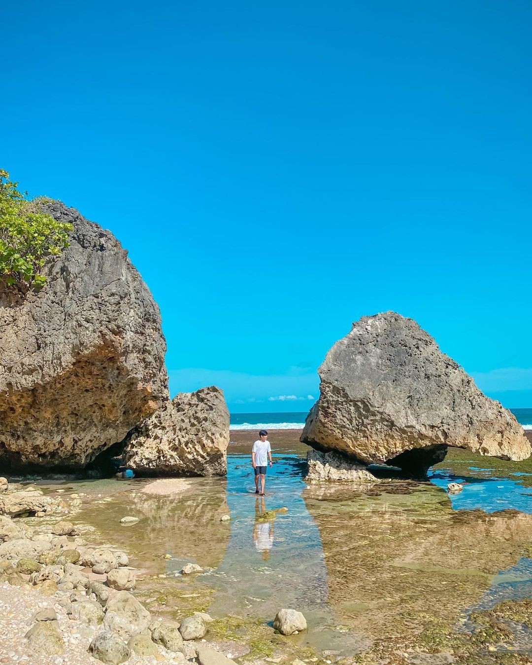 Person standing between two large rocks on Pringjono Beach.