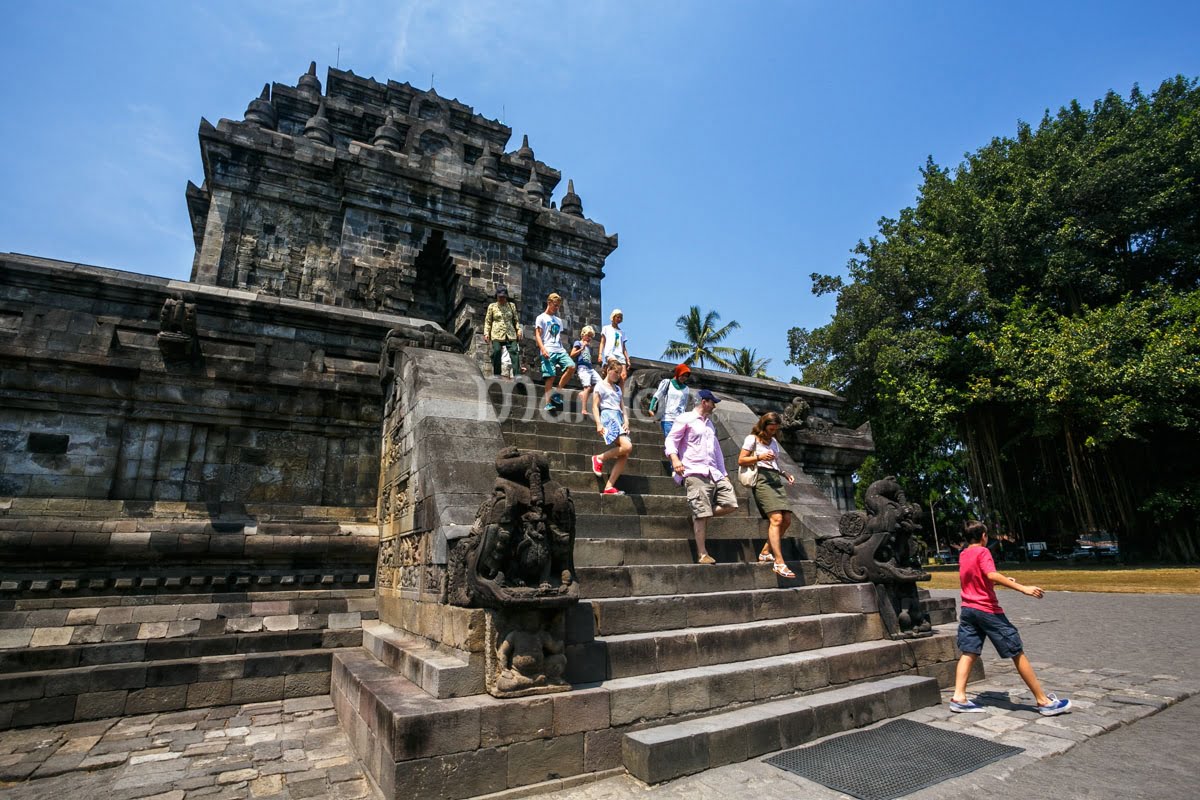 Visitors descending the stairs of Mendut Temple on a sunny day.