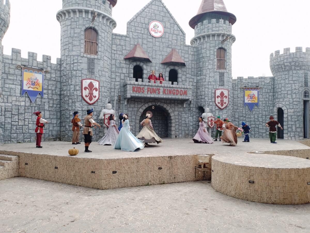 Performers in costumes acting out a fairytale scene in front of a castle at Kids Fun Park.