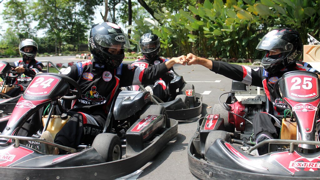 Two kids in go-karts giving a fist bump before the race.